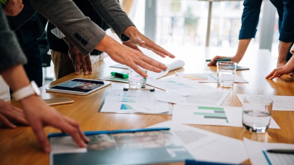 equipe analisando gráficos e documentos em uma reunião.