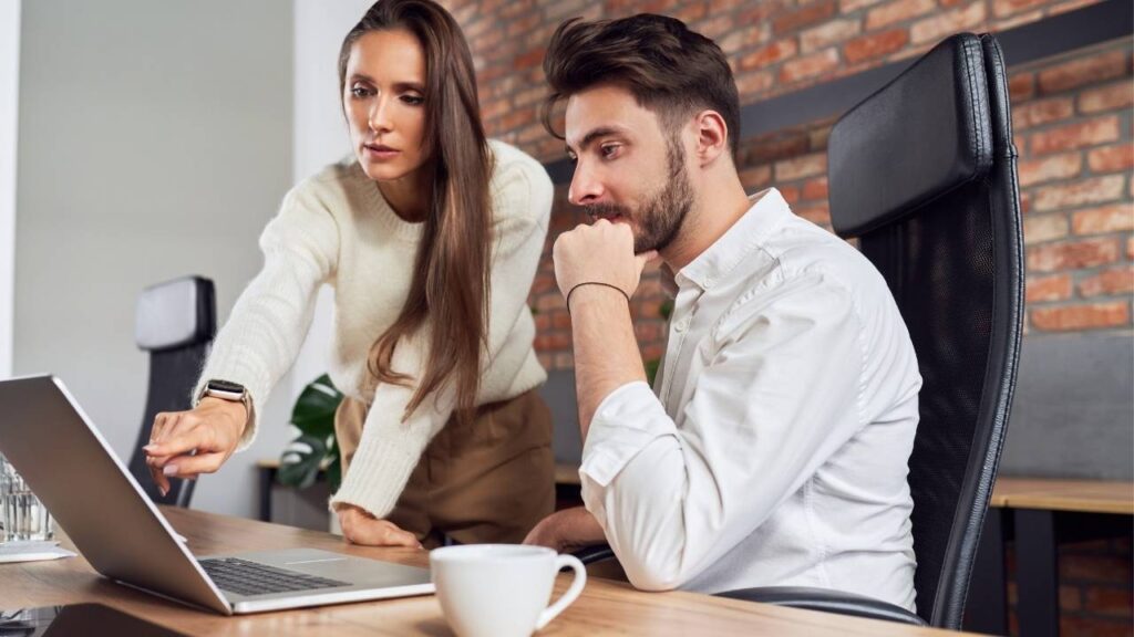 colegas discutindo estratégias de onboarding em frente a um laptop em um ambiente de escritório.