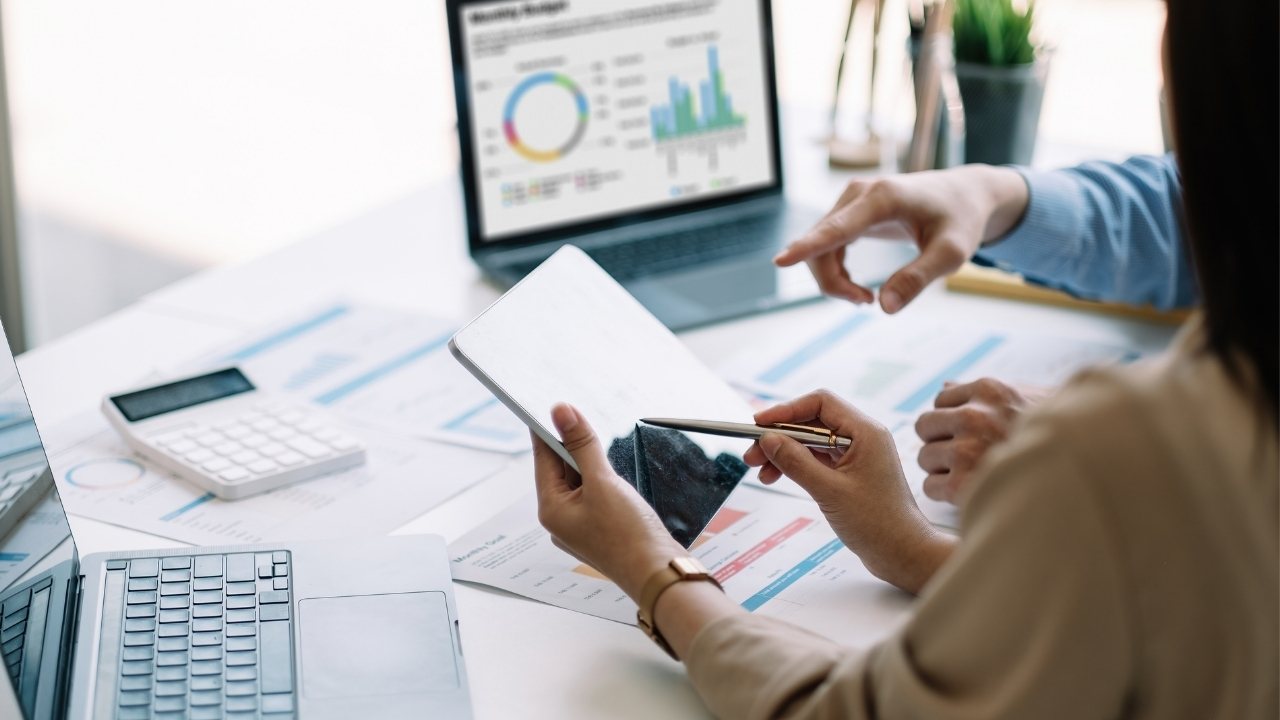 pessoas analisando gráficos e dados em dispositivos digitais.