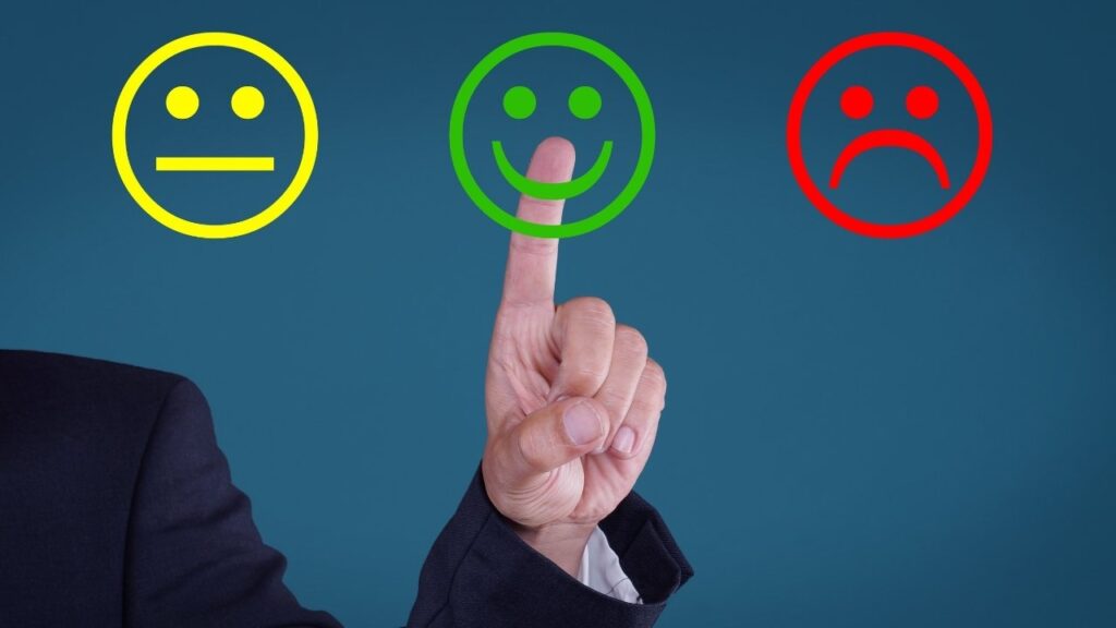 pessoa tocando um ícone de carinha feliz entre opções de avaliação.