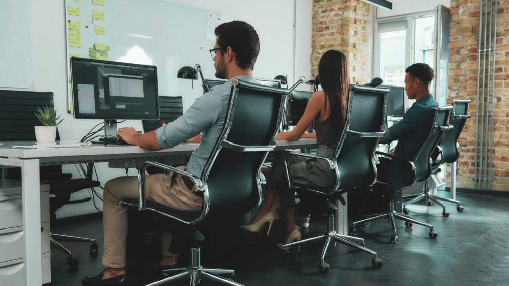 Equipe de trabalho em um escritório, concentrados em seus computadores.